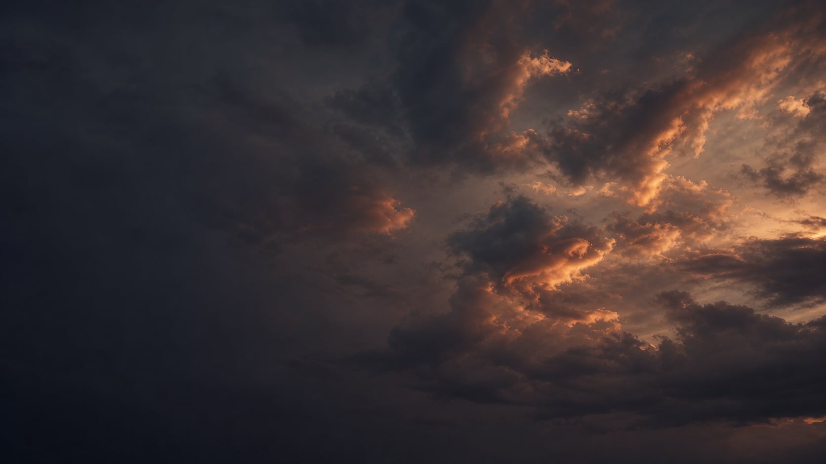 Copper evening light breaking through charcoal clouds